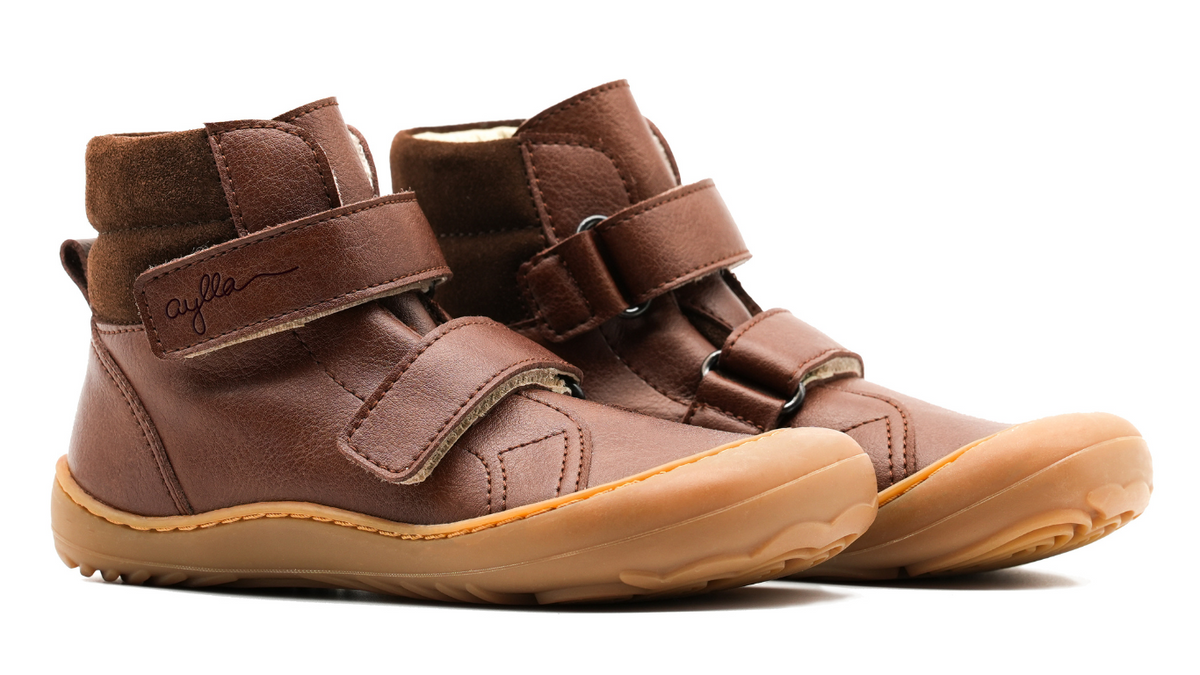 Barfußschuh für Kinder, knöchelhoch, schräge Vorderansicht. Geschlossener Schuh mit zwei Klettverschlüssen, gleichmäßige Sohlenhöhe, geschlossene Zehen.