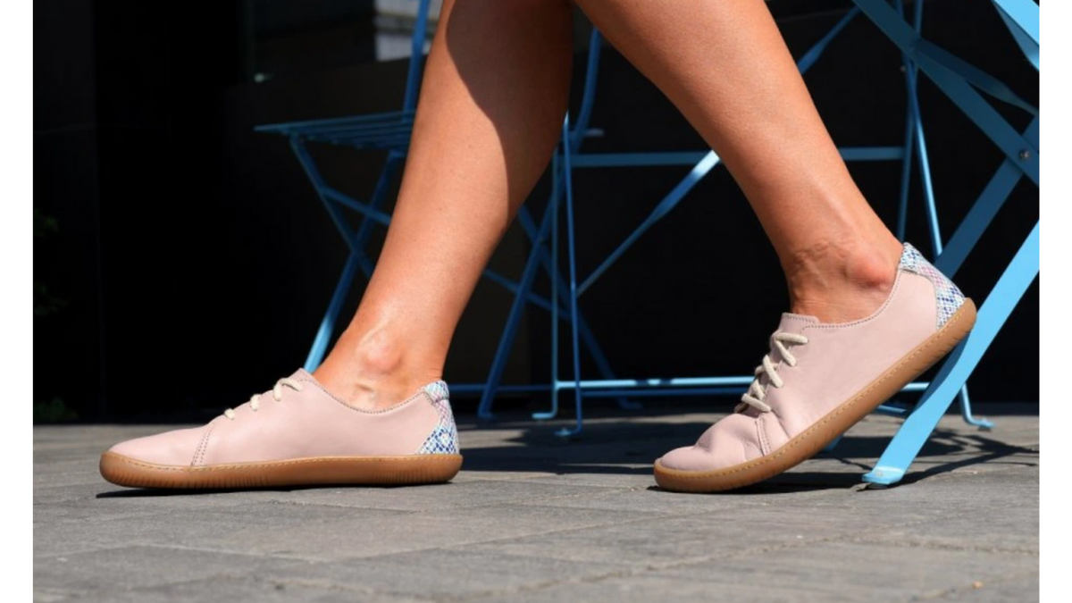 Barfußschuh für Erwachsene getragen am Fuß mit geschlossener Ferse, Schnürung und flacher flexibler Sohle, Detailansicht.