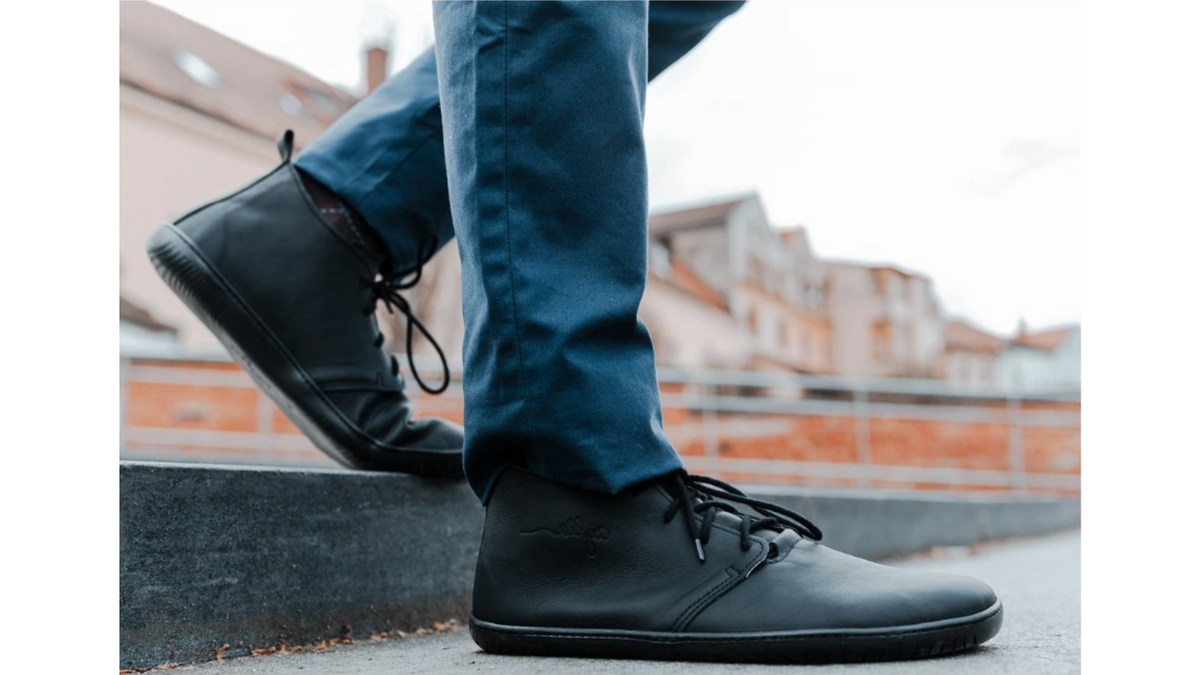 Barfußschuh für Erwachsene getragen am Fuß mit geschlossener Ferse, Schnürung und flacher flexibler Sohle, Detailansicht.