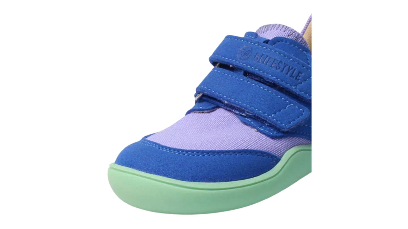 Kinder-Barfußhalbschuh mit breiter Zehenbox, flexibler Sohle und Klettverschluss, geschlossene Zehen und geschlossene Ferse, schräge Vorderansicht.