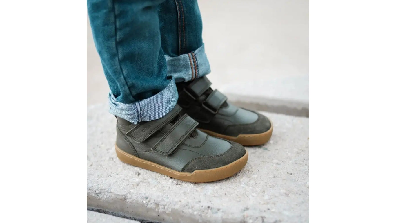 Alltagsbarfußschuh für Kinder, hoch geschnitten, mit Klettverschluss, geschlossenen Zehen und geschlossener Ferse, getragen am Fuß, schräge Vorderansicht