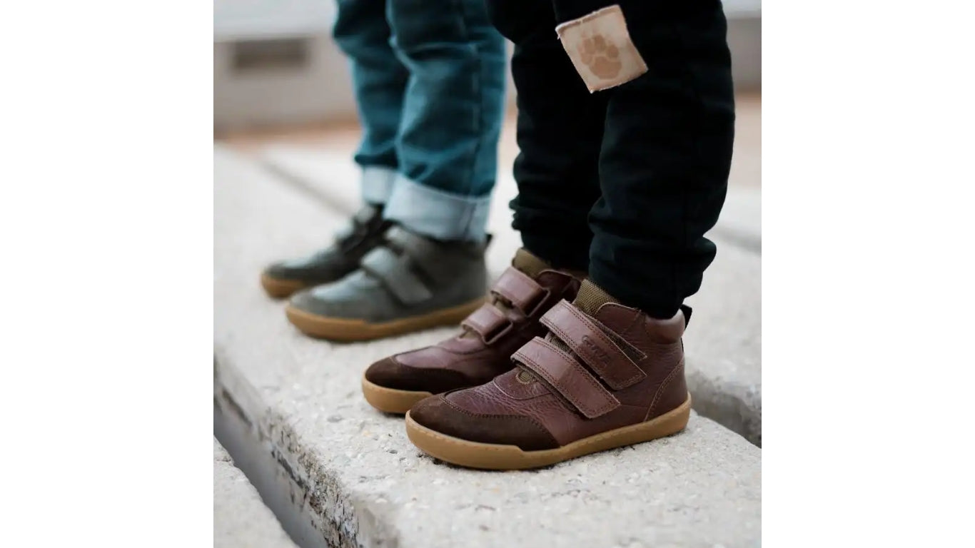 Alltagsbarfußschuh für Kinder, hoch geschnitten, mit Klettverschluss, geschlossenen Zehen und geschlossener Ferse, getragen am Fuß, schräge Vorderansicht