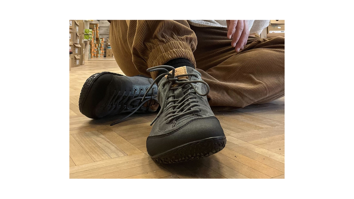Barfuß-Wanderschuh für Erwachsene getragen am Fuß mit geschlossener Ferse, Schnürung und profilierter flexibler Sohle, Detailansicht.