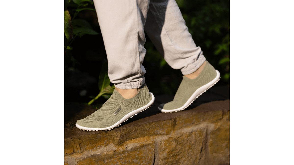 Barfußschuh mit geschlossener Zehenbox und geschlossenem Fersenbereich, elastischer Einstieg ohne Verschluss, flexible profilierte Sohle, schräge Vorderansicht am Fuß getragen