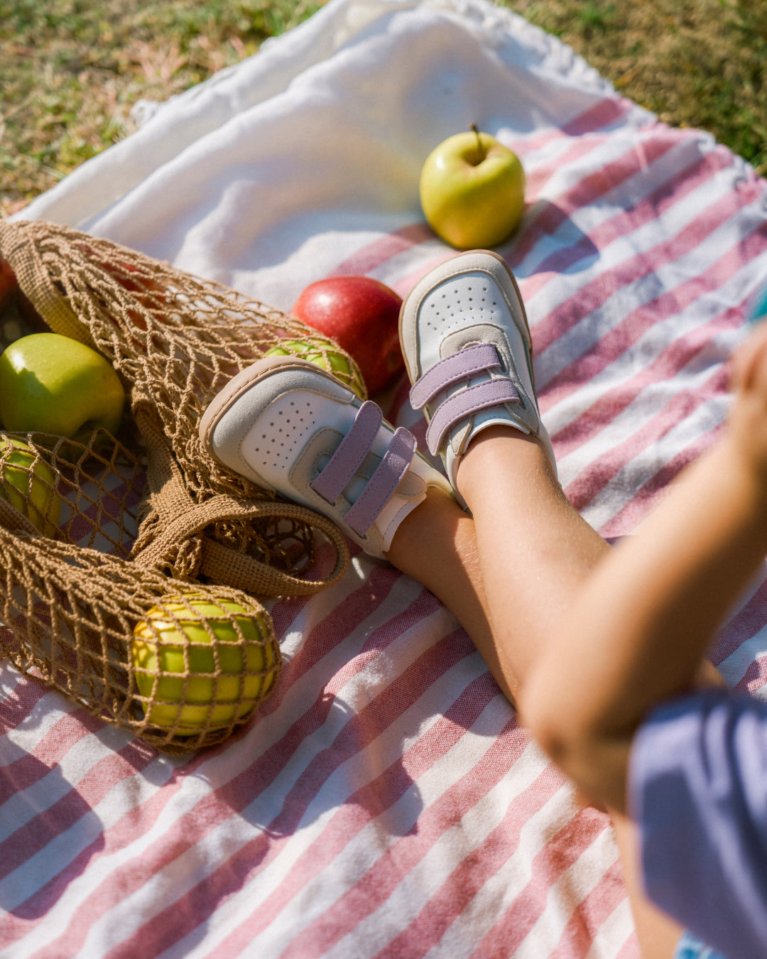 Barfußschuh für Kinder, breite Zehenbox, geschlossene Zehenpartie, geschlossener Fersenbereich, zwei Klettverschlüsse, flache Sohle, schräge Vorderansicht als Paar, getragen am Fuß