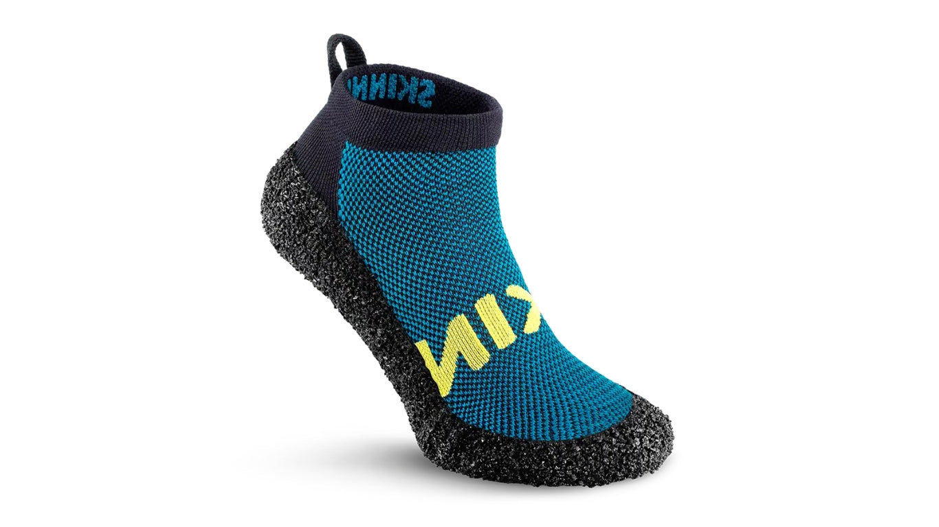 Skinners in Petrol, sockenähnlicher Schuh mit blauer Strickoberfläche, gelbem Skinners Schriftzug und schwarzer, flexibler Sohle in Seitenansicht.