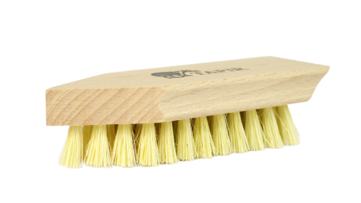 Schuhbürste mit Holzgriff in Keilform und hellem Borstenfeld, Logoaufdruck auf dem Griff, schräge Vorderansicht