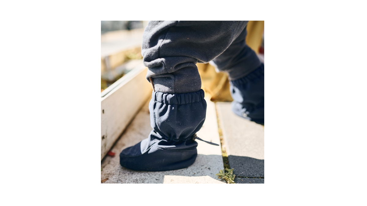 Barfußstiefel für Kinder, geschlossene Zehenpartie, geschlossener Fersenbereich, hoher Schaft mit Gummizug und Stopper, flache Sohle, Seitenansicht außen, am Fuß getragen