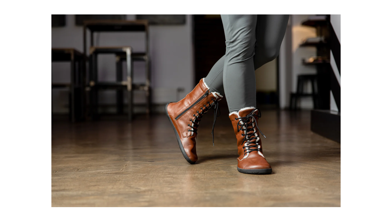 Barfußstiefel im getragenen Zustand, Seitenansicht im Innenraum. Bodennaher Kontakt, natürliche Fußhaltung.