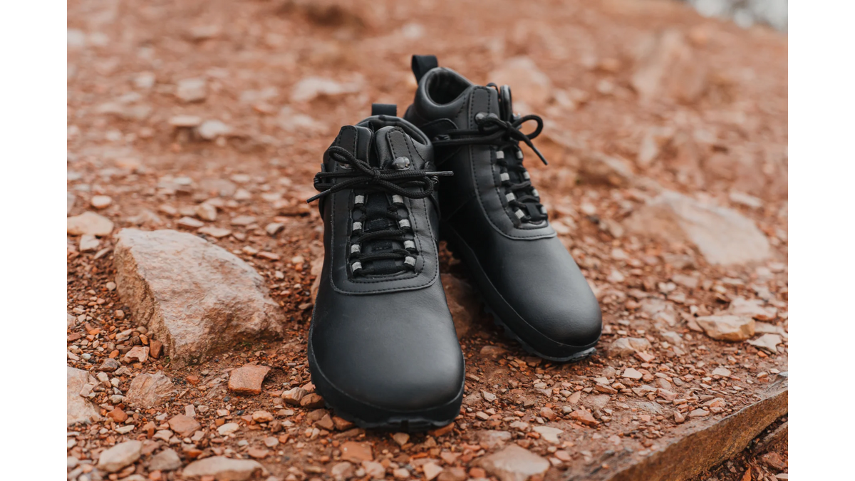 Barfußschuhe im getragenen Zustand, Frontansicht im Stand auf unebenem Untergrund. Geschlossene Zehen, flache Sohle.