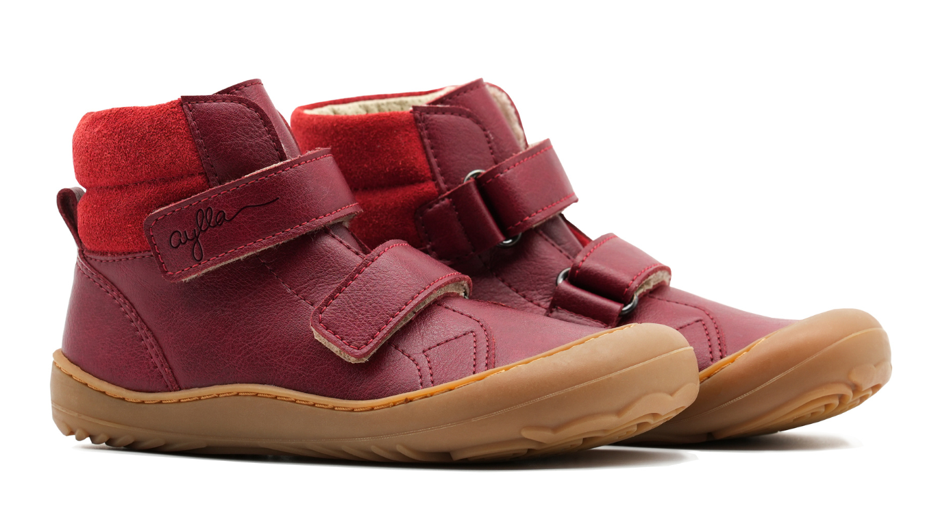 Barfußschuh für Kinder, knöchelhoch, schräge Vorderansicht. Geschlossener Schuh mit zwei Klettverschlüssen, gleichmäßige Sohlenhöhe, geschlossene Zehen.