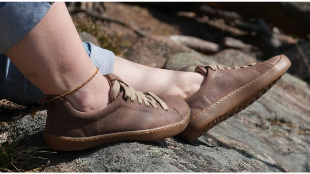 Barfußschuh im getragenen Zustand, schräge Vorderansicht. Geschlossener Schuh, Schnürung, flache flexible Sohle, natürlicher Stand.