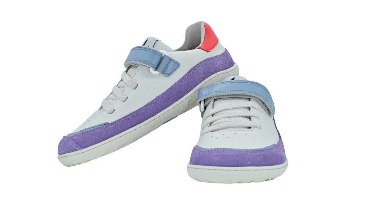 Barfußschuh für Erwachsene als Paar mit breiter Zehenbox, geschlossenem Zehenbereich, geschlossener Ferse, Klettverschluss und Schnürung, flacher flexibler Sohle, schräge Vorderansicht.