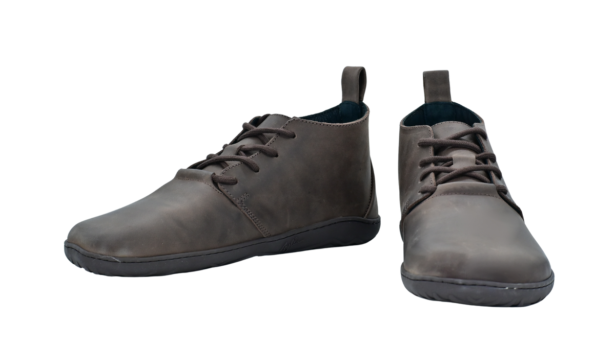 Barfußschuh für Erwachsene als Paar mit breiter Zehenbox, geschlossenem Zehenbereich, geschlossener Ferse, Schnürung, flacher flexibler Sohle, schräge Vorderansicht.