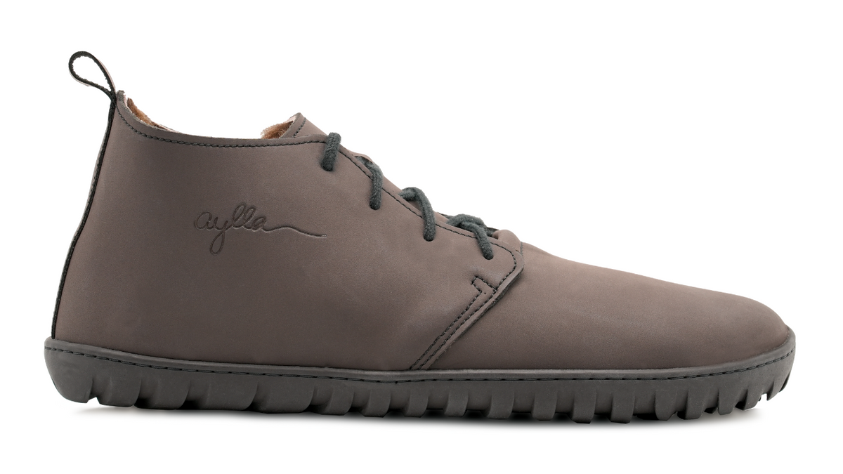 Barfußstiefel, Seitenansicht außen. Geschlossener Schuh mit Schnürung, mittelhoher Schaft, breite Zehenbox, flexible flache Sohle.