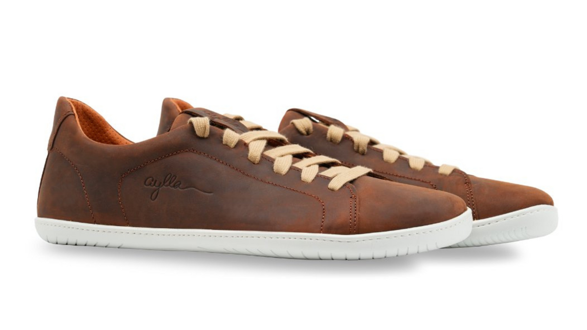 Barfußschuh für Erwachsene als Paar mit breiter Zehenbox, geschlossenem Zehenbereich, geschlossener Ferse, Schnürung, flacher flexible Sohle, schräge Vorderansicht.