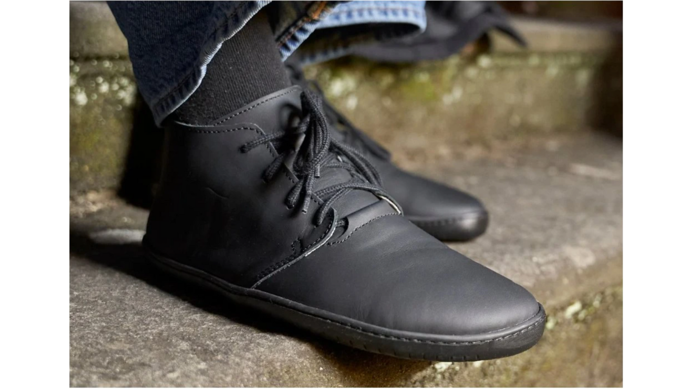Barfußschuh für Erwachsene getragen am Fuß mit geschlossener Ferse, Schnürung und flacher flexibler Sohle, Detailansicht.