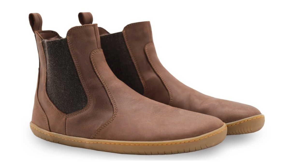 Barfußstiefel als Paar, schräge Vorderansicht. Knöchelhoch, elastische Seiteneinsätze, breite Zehenbox, symmetrische Form.