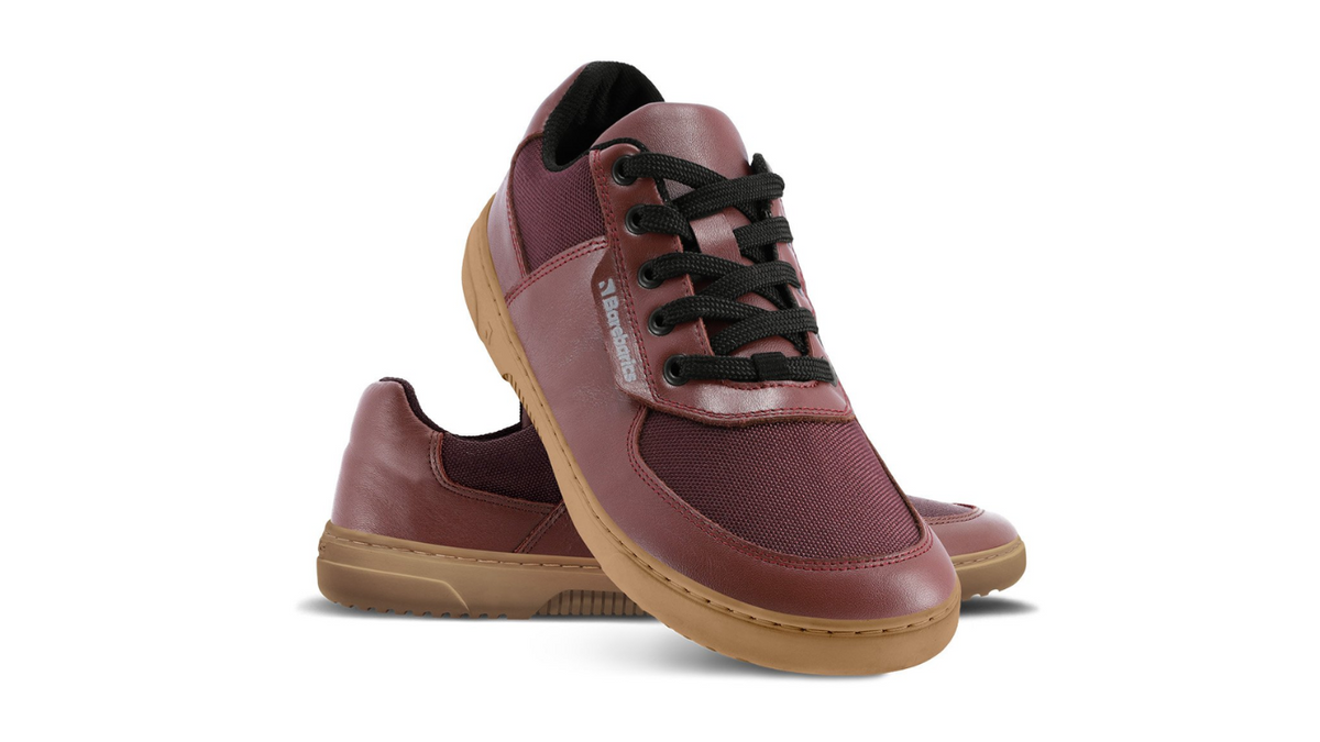 Barfußschuh für Erwachsene als Paar mit breiter Zehenbox, geschlossenem Zehenbereich, geschlossener Ferse, Schnürung, flacher flexibler Sohle, schräge Vorderansicht.