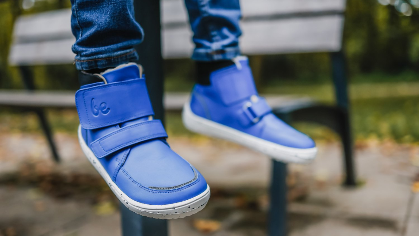 Barfußwinterstiefel für Kinder am Fuß getragen mit Klettverschluss, knöchelhohem Schaft und geschlossener Ferse, schräge Vorderansicht.