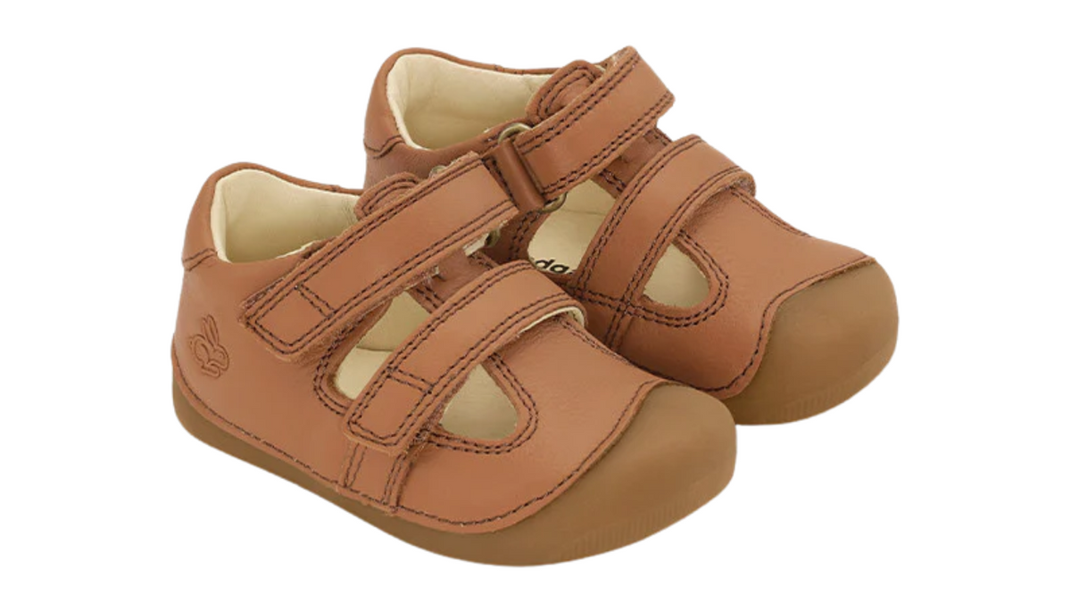 Kinder-Barfußschuh mit breiter Zehenbox, geschlossenem Zehenbereich, geschlossenem Fersenbereich, Riemenkonstruktion mit Verschluss, flacher flexibler Sohle, schräge Vorderansicht.