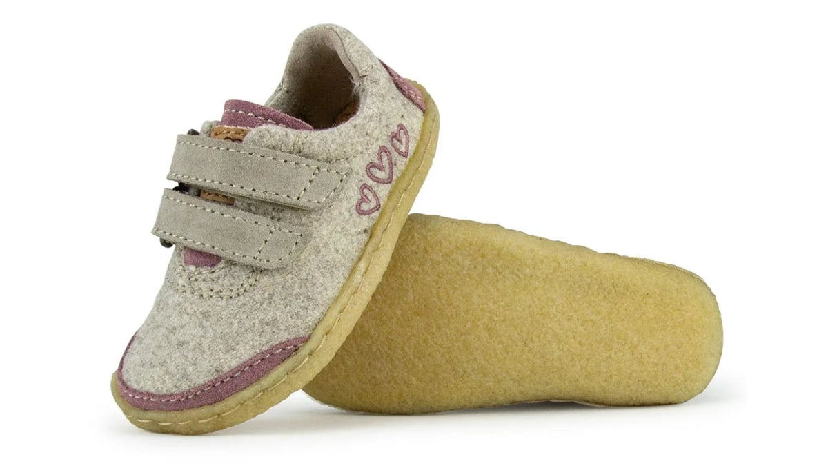 Barfußschuh für Kinder mit geschlossener Zehenbox, zwei Klettverschlüssen und flexibler Sohle, Schuh auf der Seite liegend. Schräge Vorderansicht.