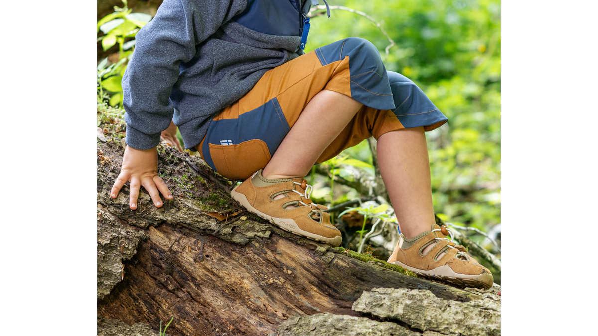 Kinder-Barfußsandale getragen am Fuß mit geschlossenem Fersenbereich, Schnürsystem mit Kordel, flexible Sohle, Detailansicht.