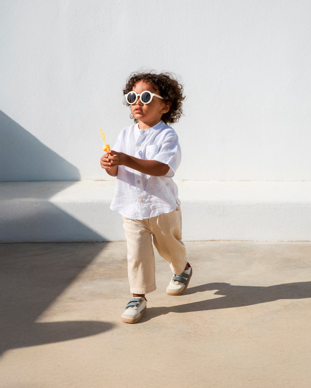 Barfußschuh für Kinder, breite Zehenbox, geschlossene Zehenpartie, geschlossener Fersenbereich, zwei Klettverschlüsse, flache Sohle, schräge Vorderansicht als Paar, getragen am Fuß