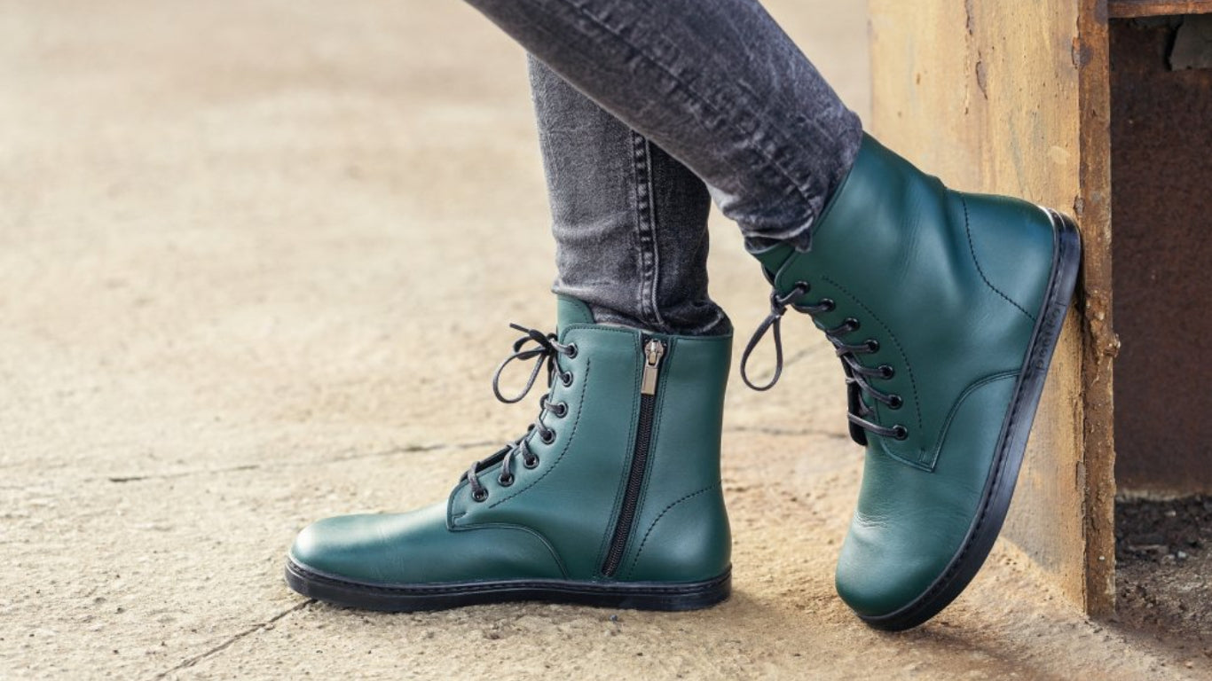 Barfußstiefel mit Schnürverschluss am Fuß getragen, breiter Zehenbox und flacher Sohle, geschlossener Fersenbereich, schräge Vorderansicht