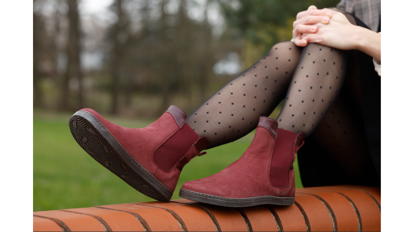 Barfußstiefel mit elastischem Einsatz am Fuß getragen, breiter Zehenbox und flacher Sohle, geschlossener Fersenbereich, schräge Vorderansicht