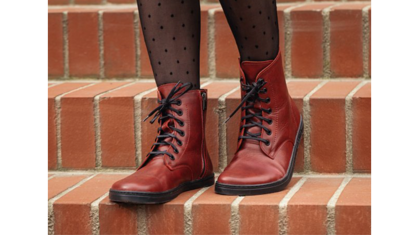 Barfußstiefel mit Schnürverschluss am Fuß getragen, breiter Zehenbox und flacher Sohle, geschlossener Fersenbereich, schräge Vorderansicht