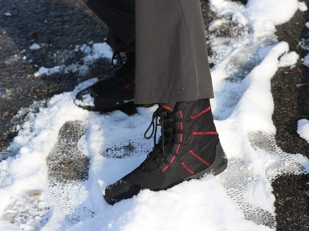 Barfußwinterstiefel für Erwachsene mit Schnürung und geschlossenem Schaft am Fuß getragen, schräge Vorderansicht