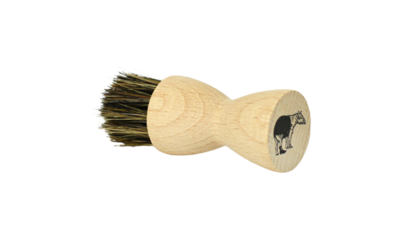 Auftragbürste mit rundem Holzgriff und dichtem Borstenkopf, Logoaufdruck auf der Stirnseite, schräge Vorderansicht