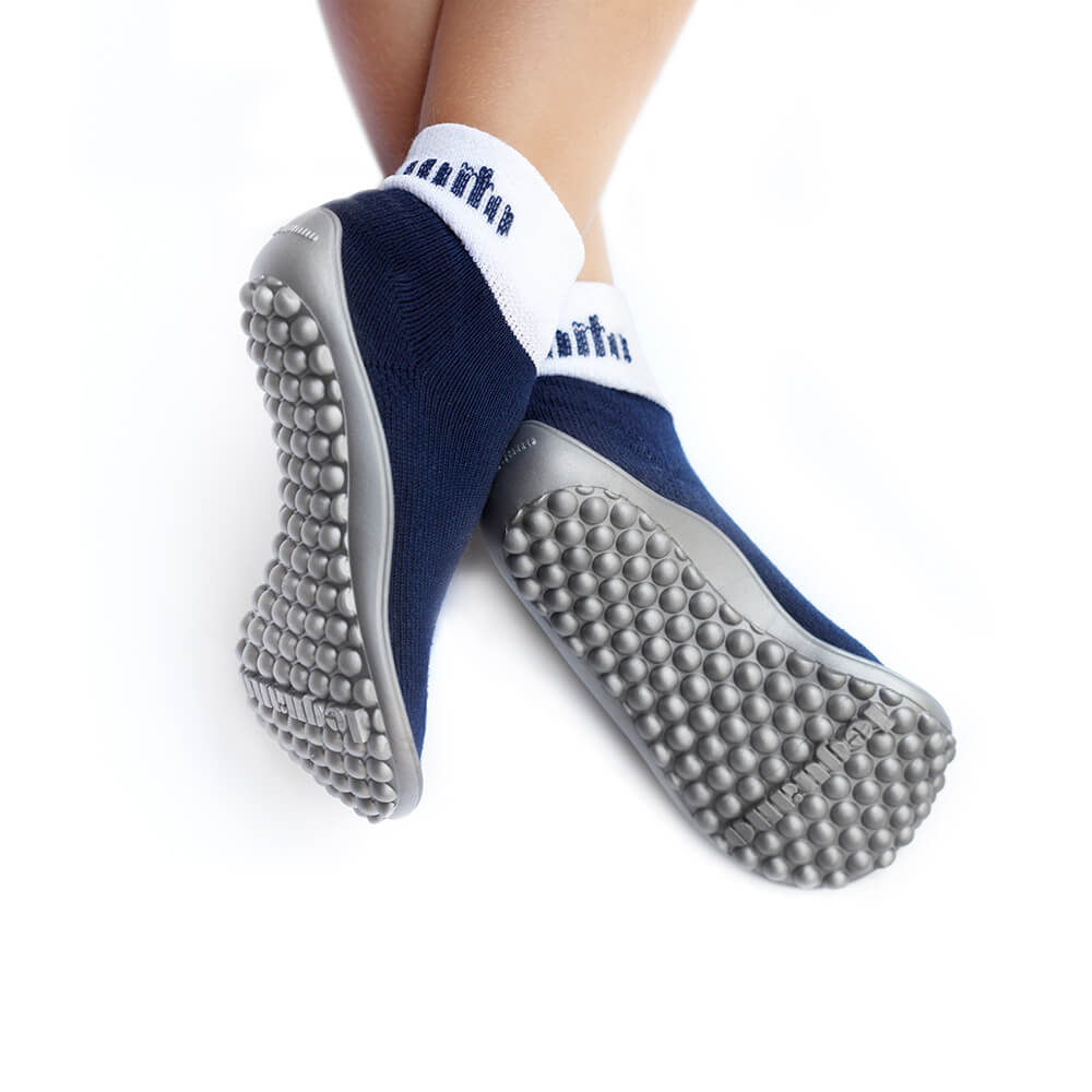 Barfußschuh mit geschlossener Zehenbox und geschlossenem Fersenbereich, elastischer Schaft ohne Verschluss, flexible Sohle mit runden Profilnoppen, Ansicht von unten am Fuß getragen