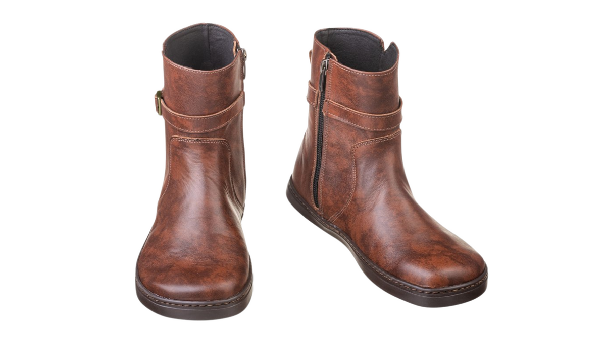 Barfußstiefel als Paar mit seitlichem Reißverschluss und Riemen, breiter Zehenbox und flacher Sohle, geschlossener Fersenbereich, schräge Vorderansicht